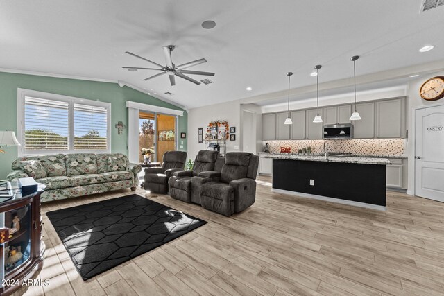 living room with ceiling fan, light wood-type flooring, and vaulted ceiling