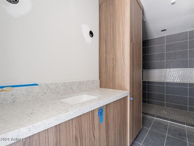 bathroom featuring tile patterned flooring, vanity, and tiled shower