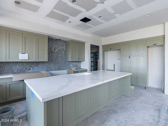 kitchen with tasteful backsplash, gray cabinets, light stone countertops, and a kitchen island