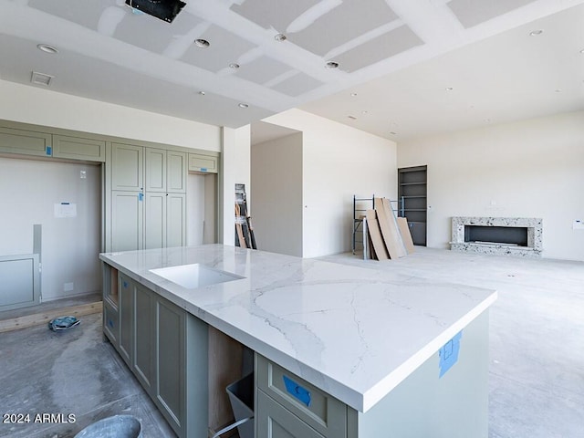 kitchen featuring gray cabinetry, a center island, light stone countertops, and concrete flooring