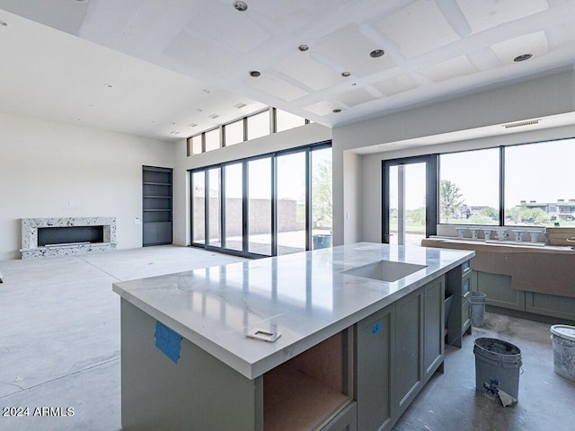 kitchen featuring a center island, concrete floors, gray cabinetry, and coffered ceiling