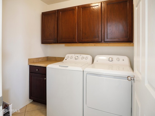 laundry area featuring light tile patterned floors, cabinet space, washer and dryer, and baseboards