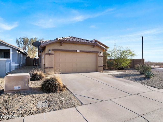 view of home's exterior with stucco siding, driveway, fence, an attached garage, and a tiled roof