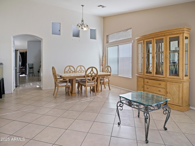 dining space featuring light tile patterned floors, visible vents, baseboards, an inviting chandelier, and arched walkways