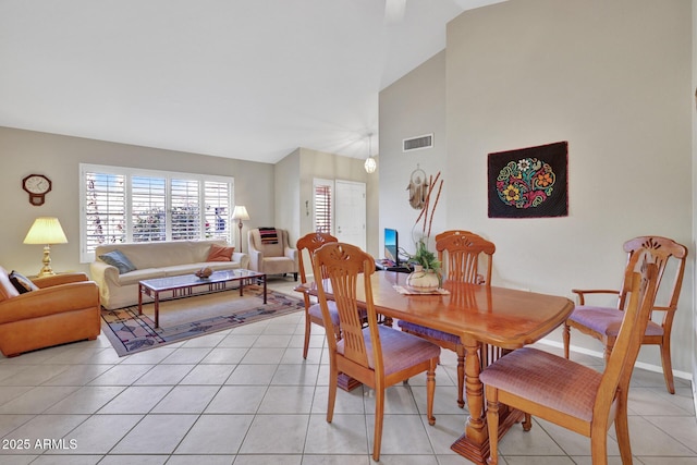 dining area with light tile patterned flooring and high vaulted ceiling