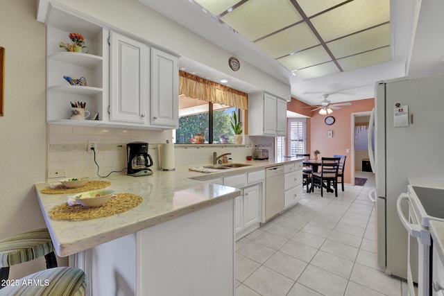 kitchen featuring white cabinetry, sink, white appliances, and kitchen peninsula