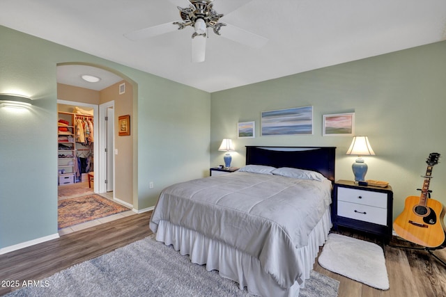 bedroom with wood-type flooring, a spacious closet, ceiling fan, and a closet