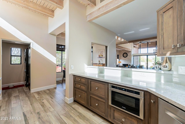 kitchen featuring light hardwood / wood-style floors, light stone countertops, backsplash, and stainless steel oven