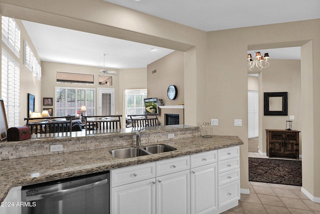 kitchen with stone counters, sink, stainless steel dishwasher, light tile patterned floors, and white cabinetry