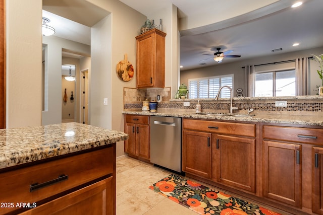 kitchen with dishwasher, backsplash, light stone counters, and sink