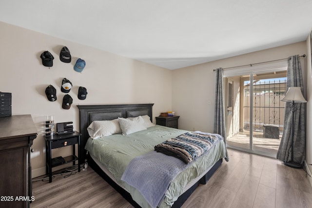 bedroom featuring access to exterior, baseboards, and wood finished floors