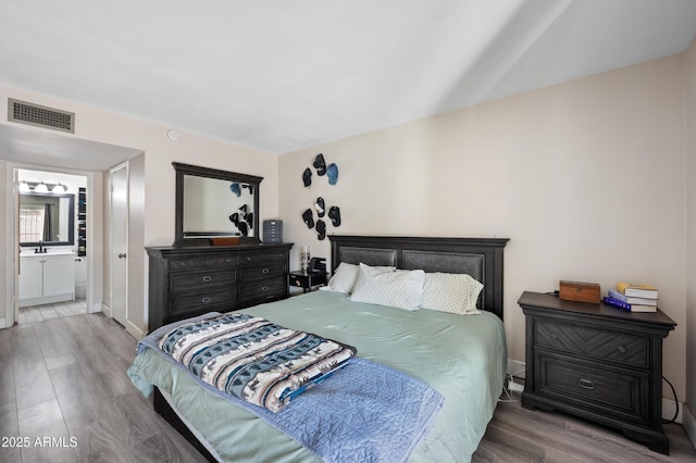 bedroom featuring a sink, ensuite bath, wood finished floors, and visible vents