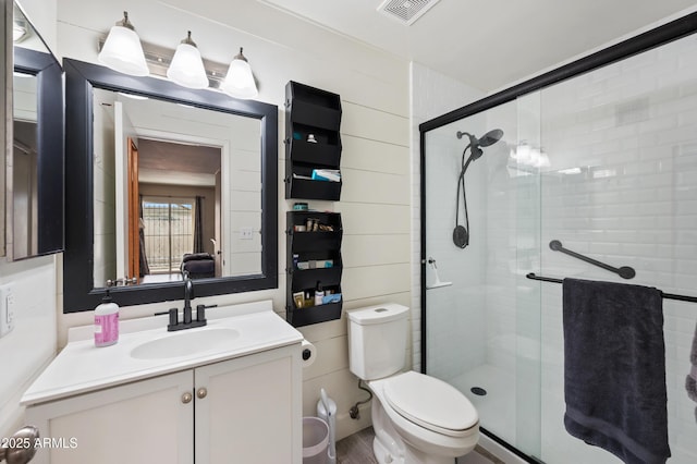 full bath with a stall shower, visible vents, vanity, and toilet