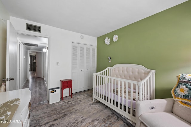 bedroom featuring a nursery area, a closet, and visible vents