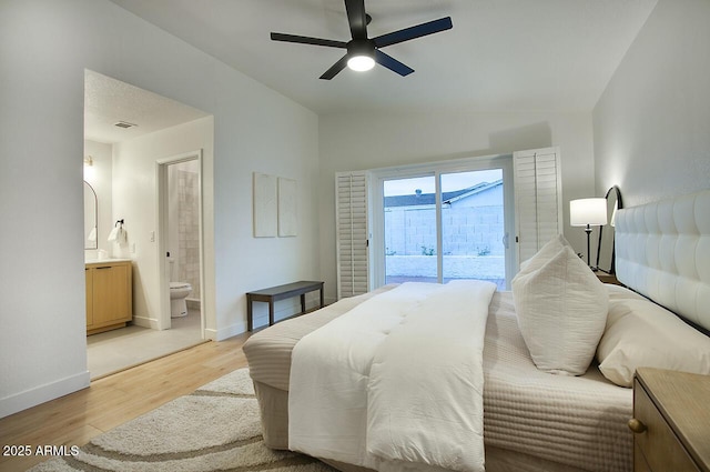 bedroom with baseboards, lofted ceiling, access to exterior, light wood-style floors, and ensuite bath