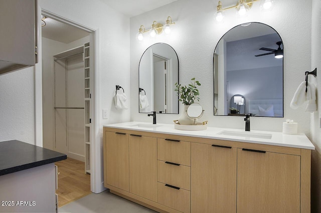 full bathroom with double vanity, wood finished floors, a sink, and a ceiling fan
