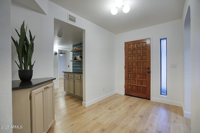 entrance foyer with baseboards, visible vents, light wood-style flooring, and a textured ceiling
