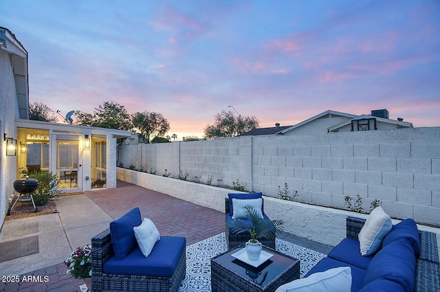 patio terrace at dusk with a fenced backyard, an outdoor hangout area, and area for grilling