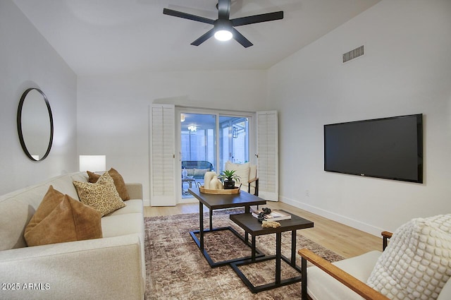 living room featuring baseboards, ceiling fan, visible vents, and wood finished floors