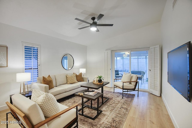 living room with lofted ceiling, baseboards, light wood finished floors, and ceiling fan
