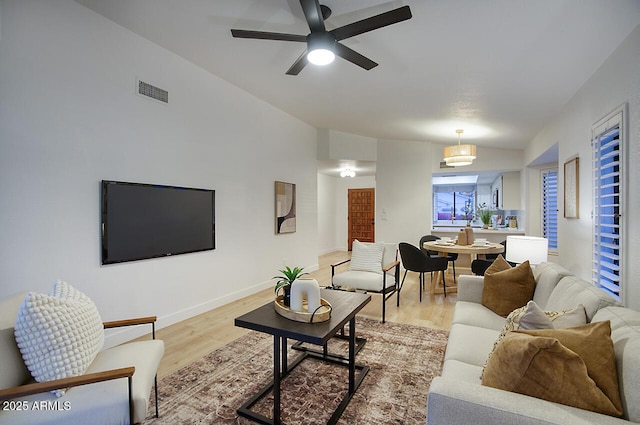 living room with visible vents, light wood-style flooring, baseboards, a ceiling fan, and lofted ceiling