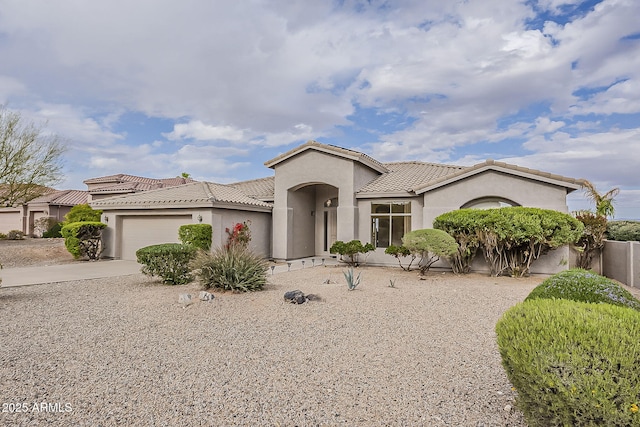 mediterranean / spanish house featuring a tiled roof, a garage, driveway, and stucco siding