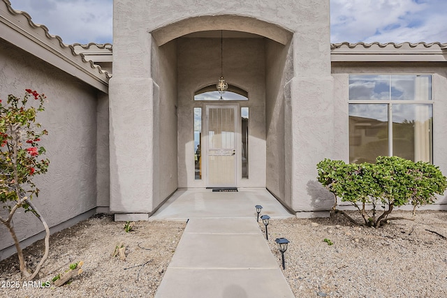 property entrance featuring a tile roof and stucco siding