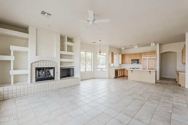 unfurnished living room featuring built in features, a ceiling fan, visible vents, light tile patterned flooring, and a fireplace