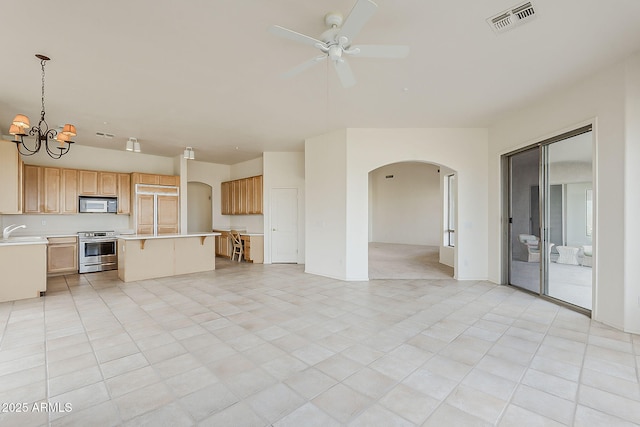 unfurnished living room with a sink, visible vents, arched walkways, and ceiling fan with notable chandelier