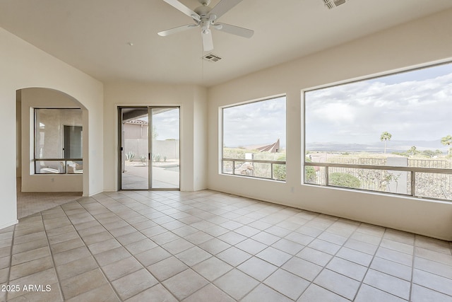 unfurnished room featuring light tile patterned flooring, visible vents, arched walkways, and ceiling fan