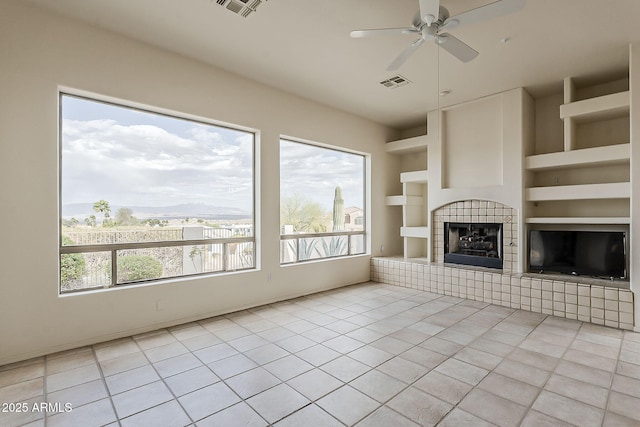 unfurnished living room featuring a wealth of natural light, visible vents, built in shelves, and a tile fireplace