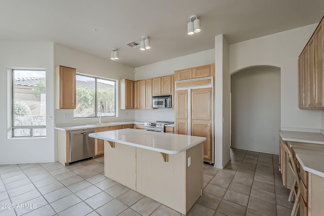 kitchen with visible vents, a center island, stainless steel appliances, arched walkways, and light countertops