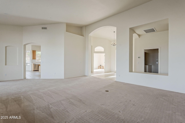 spare room with visible vents, light colored carpet, high vaulted ceiling, and a notable chandelier