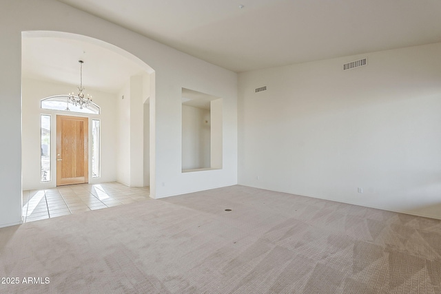 empty room featuring tile patterned floors, visible vents, carpet, and a notable chandelier