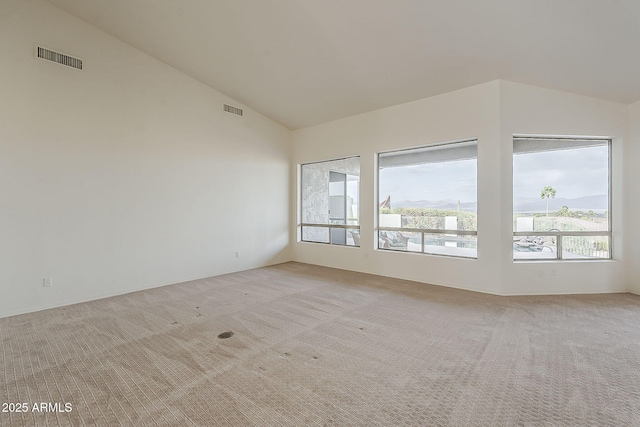 empty room featuring visible vents, light colored carpet, and high vaulted ceiling