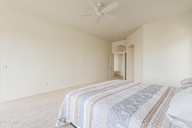 bedroom with ceiling fan, arched walkways, and light carpet