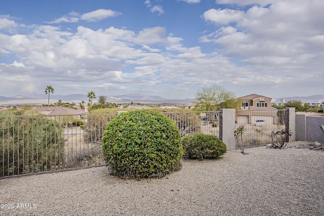 view of yard with a fenced front yard, a mountain view, and a gate