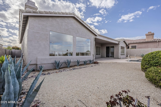 rear view of house featuring a tile roof, a patio area, a fenced backyard, and stucco siding