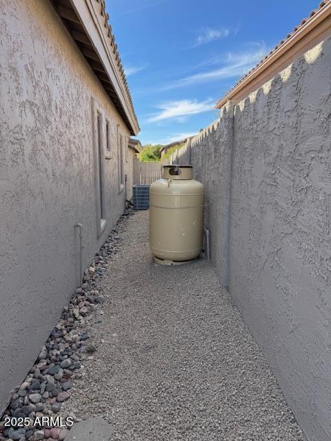 view of side of property featuring fence, central AC, and stucco siding