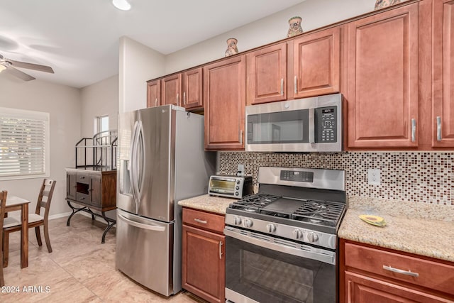 kitchen featuring stainless steel appliances, ceiling fan, tasteful backsplash, and light stone countertops