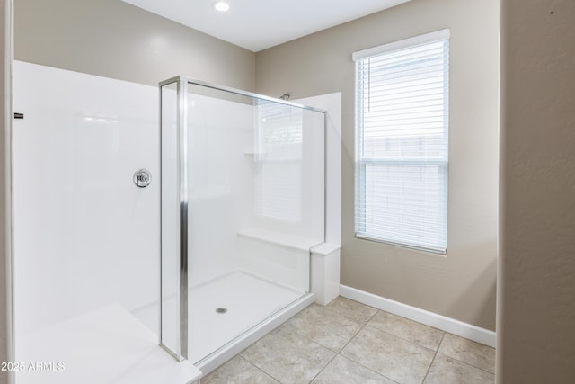 full bathroom with a stall shower, tile patterned floors, and baseboards