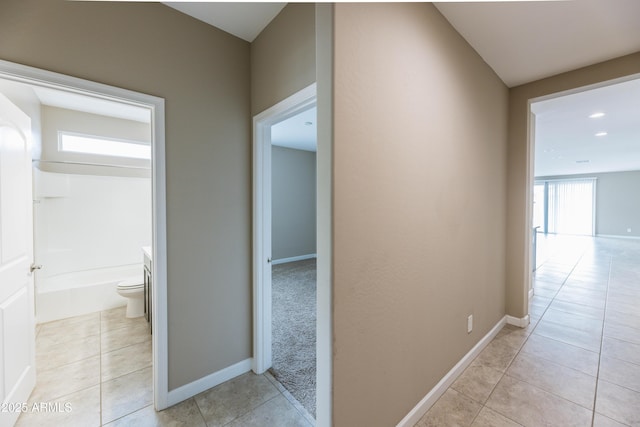 hall with baseboards and light tile patterned floors
