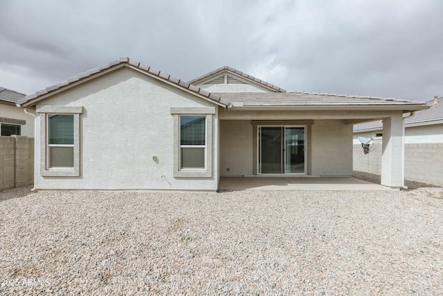 back of property featuring a tiled roof, stucco siding, fence, and a patio