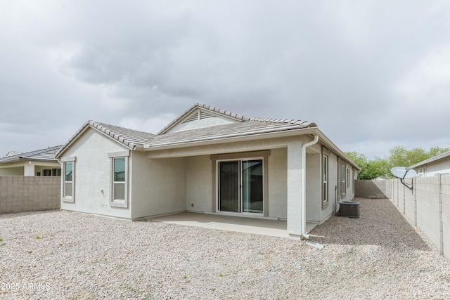 rear view of house with a tiled roof, central AC, a fenced backyard, stucco siding, and a patio area