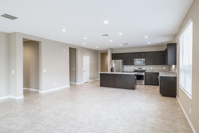 kitchen with stainless steel appliances, baseboards, a center island, and recessed lighting