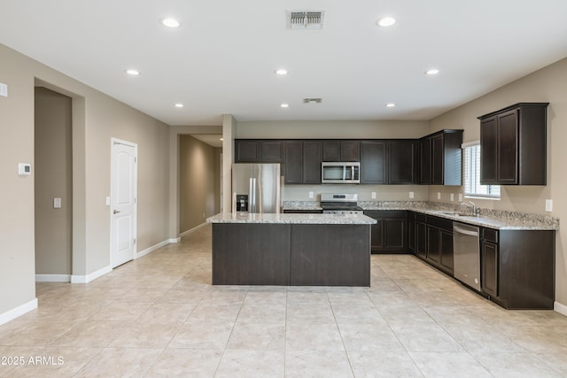 kitchen featuring a center island, visible vents, light stone counters, and appliances with stainless steel finishes