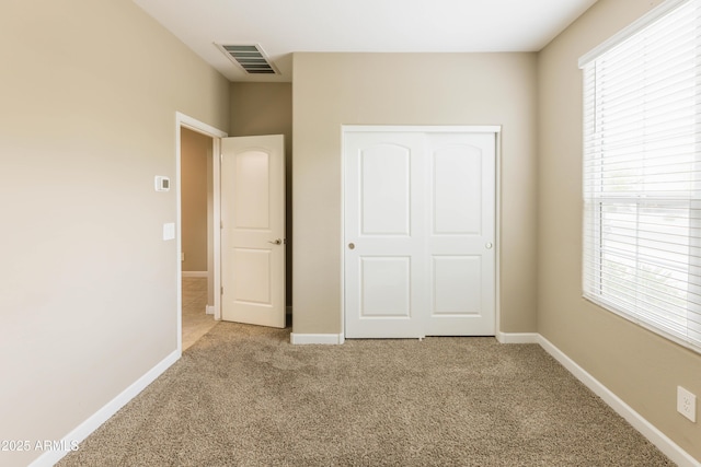 unfurnished bedroom featuring light carpet, baseboards, and visible vents
