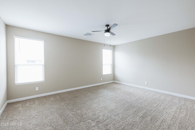 empty room with carpet floors, baseboards, ceiling fan, and visible vents