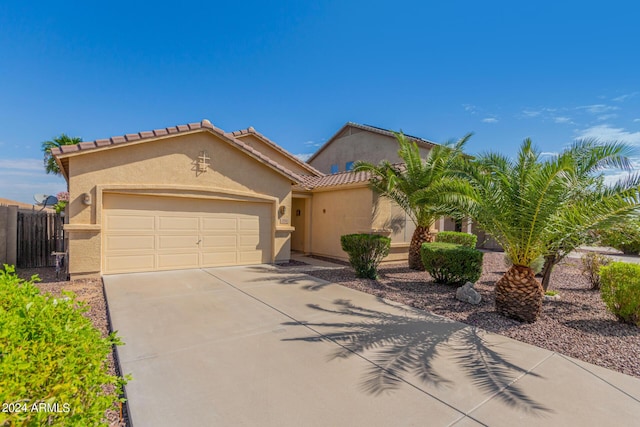 mediterranean / spanish-style house featuring a garage, fence, driveway, a tiled roof, and stucco siding