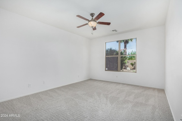 carpeted spare room with visible vents and a ceiling fan